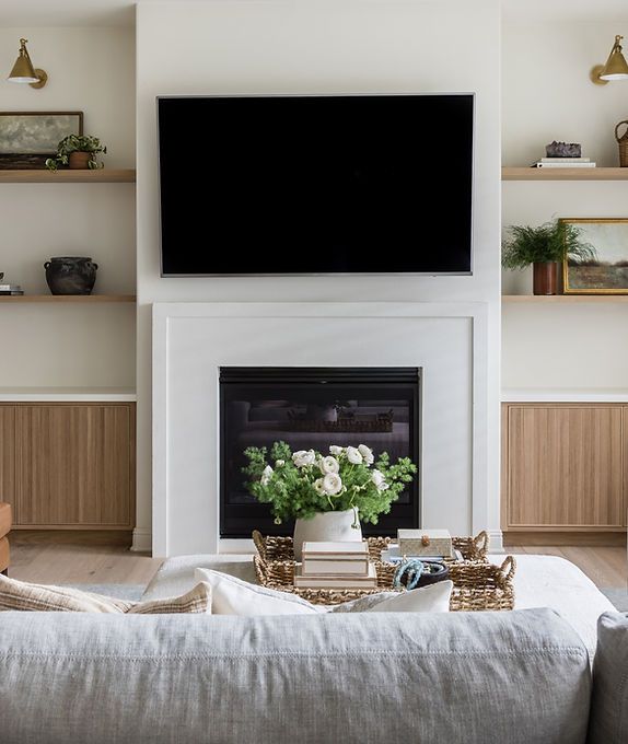 a large flat screen tv mounted above a fireplace in a living room with wooden shelves