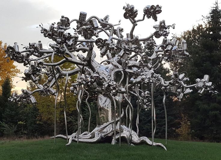 a large metal tree sculpture sitting on top of a lush green field