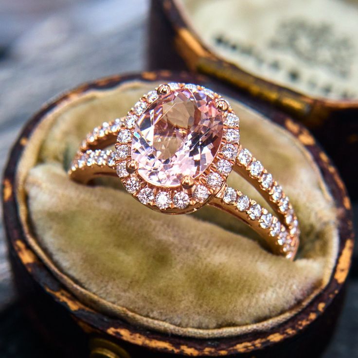 a pink diamond ring sitting on top of a velvet box with an old - fashioned band