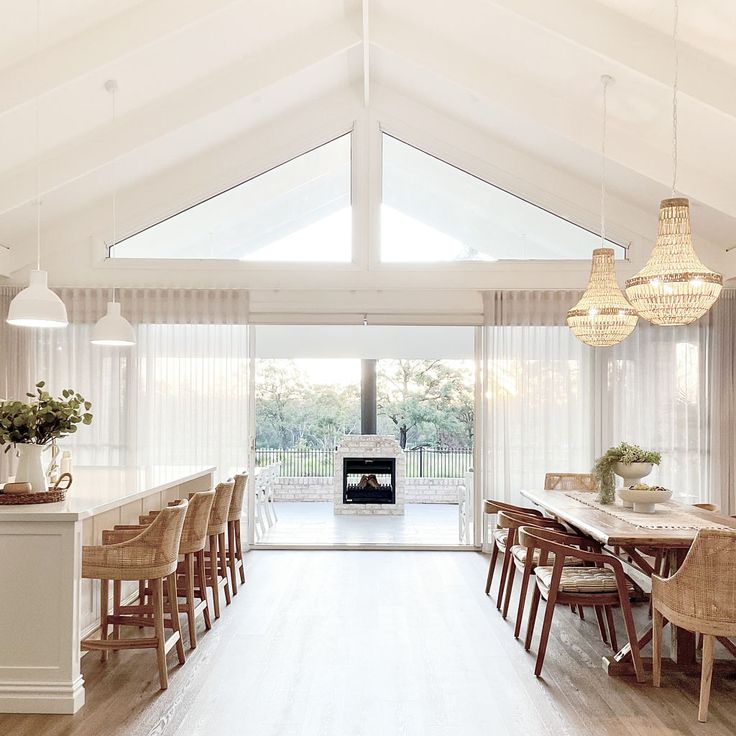 a dining room with white walls and wooden chairs, an open fireplace in the center