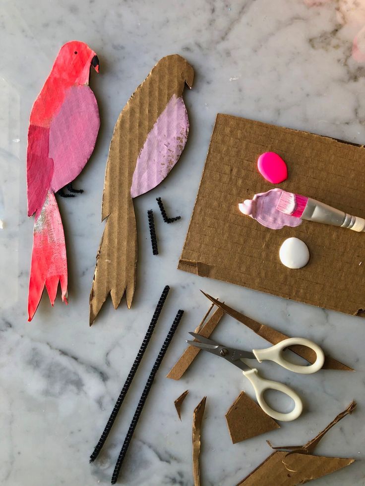 some paper birds are sitting on top of cardboard and other crafting supplies that include scissors