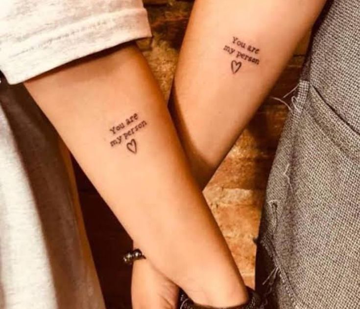 two people holding hands with tattoos on their arms