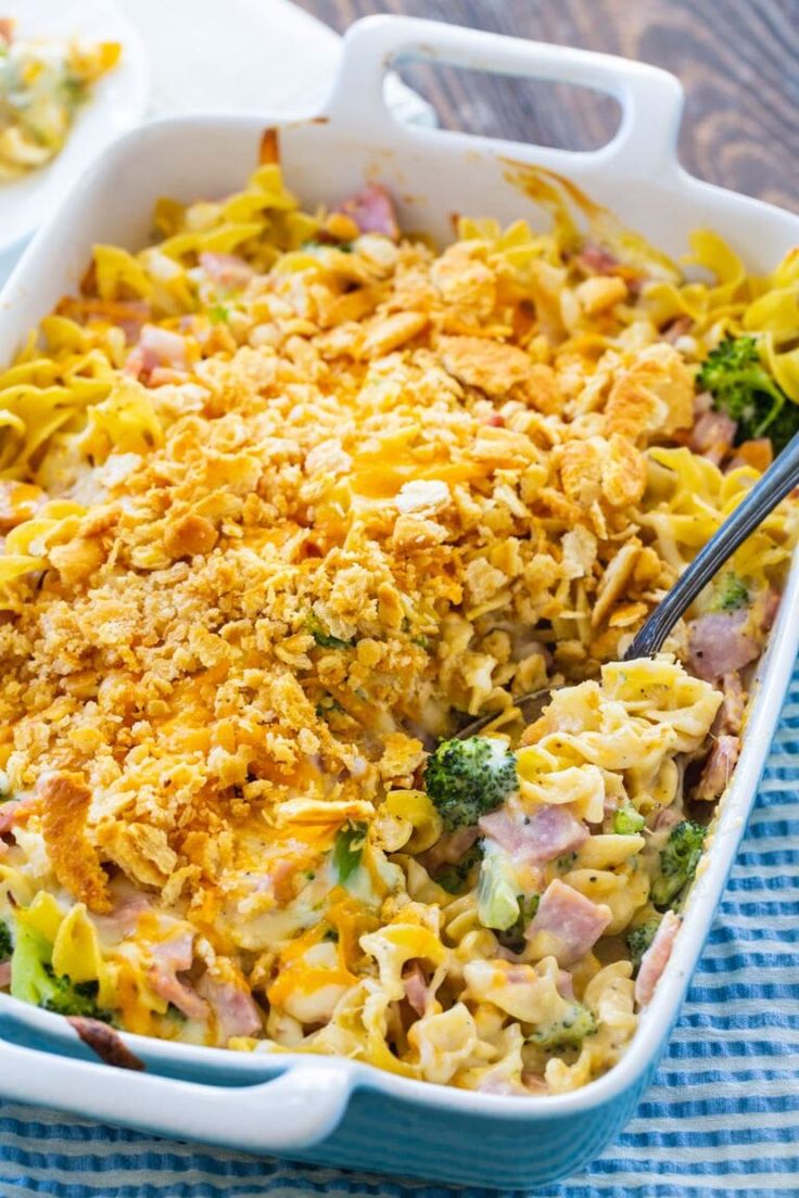 a casserole dish with broccoli, ham and noodles in it on a blue towel