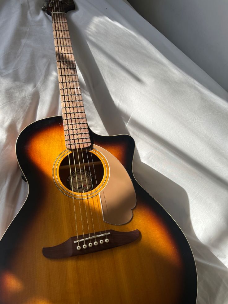 an acoustic guitar laying on top of a white sheet with the strings still attached to it