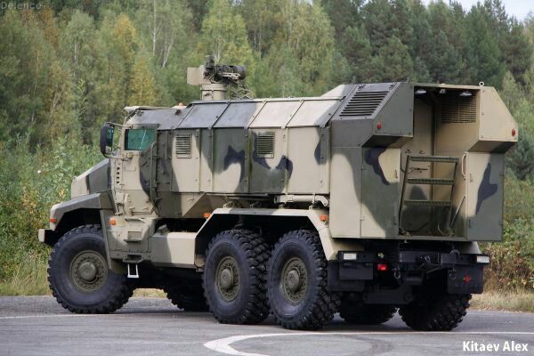 an army truck is parked on the side of the road with trees in the background