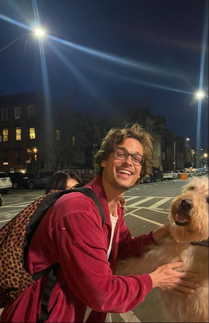 a man holding a dog on the street at night