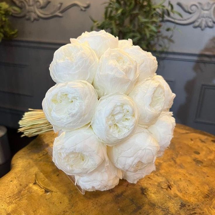 a bouquet of white flowers sitting on top of a wooden table