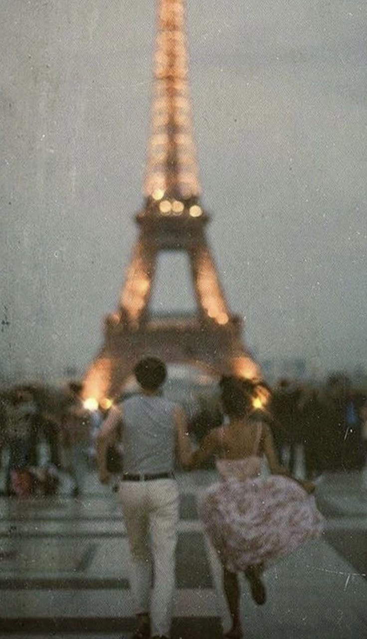 two people walking in front of the eiffel tower