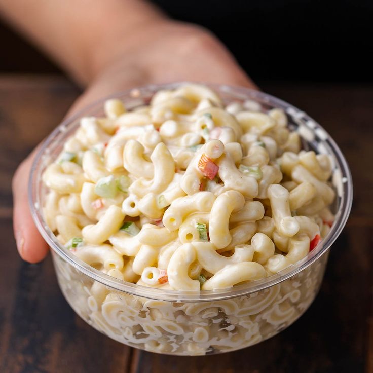 a person holding a bowl of macaroni salad