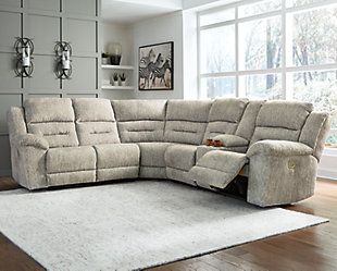 a living room with a large sectional couch and white rug in front of the window