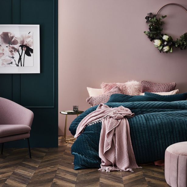 a bedroom with purple walls, green bedding and two chairs in front of the bed