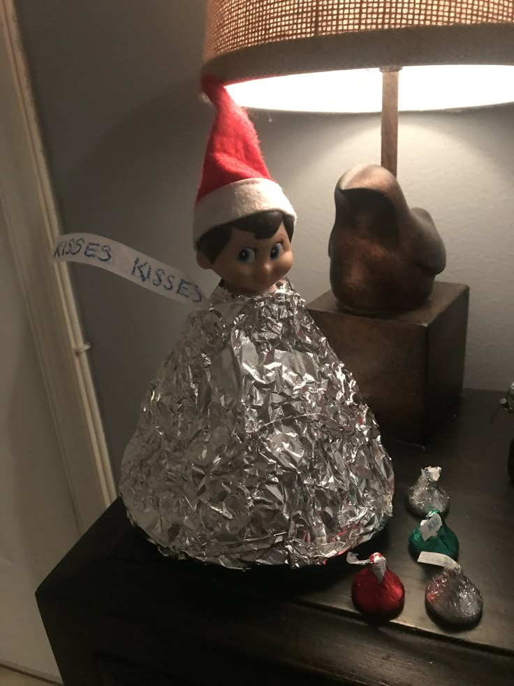 an elf is sitting on top of a table with tin foil wrapped around it and candy