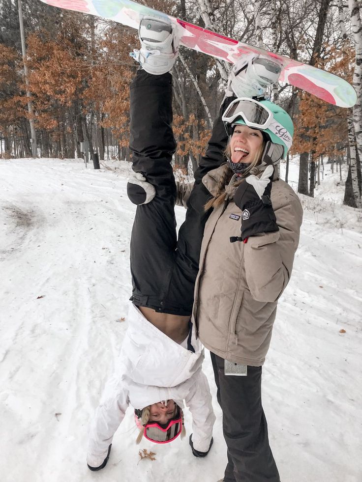 a woman holding up a snowboard above her head