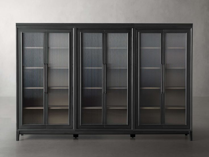 an empty bookcase with glass doors in front of a white wall and grey floor