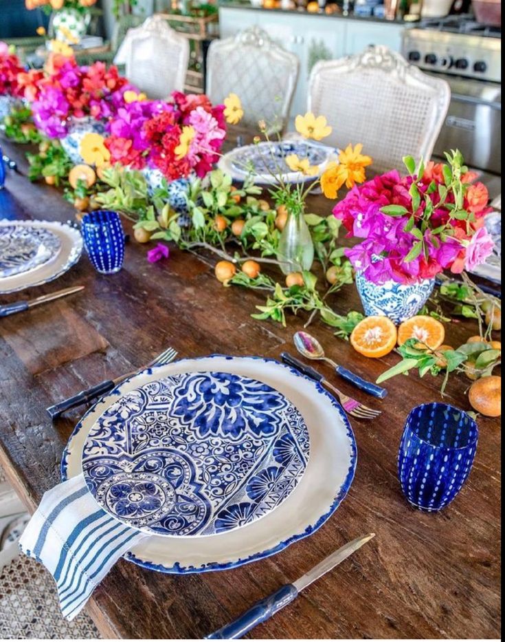 a wooden table topped with blue and white plates next to flowers on top of it