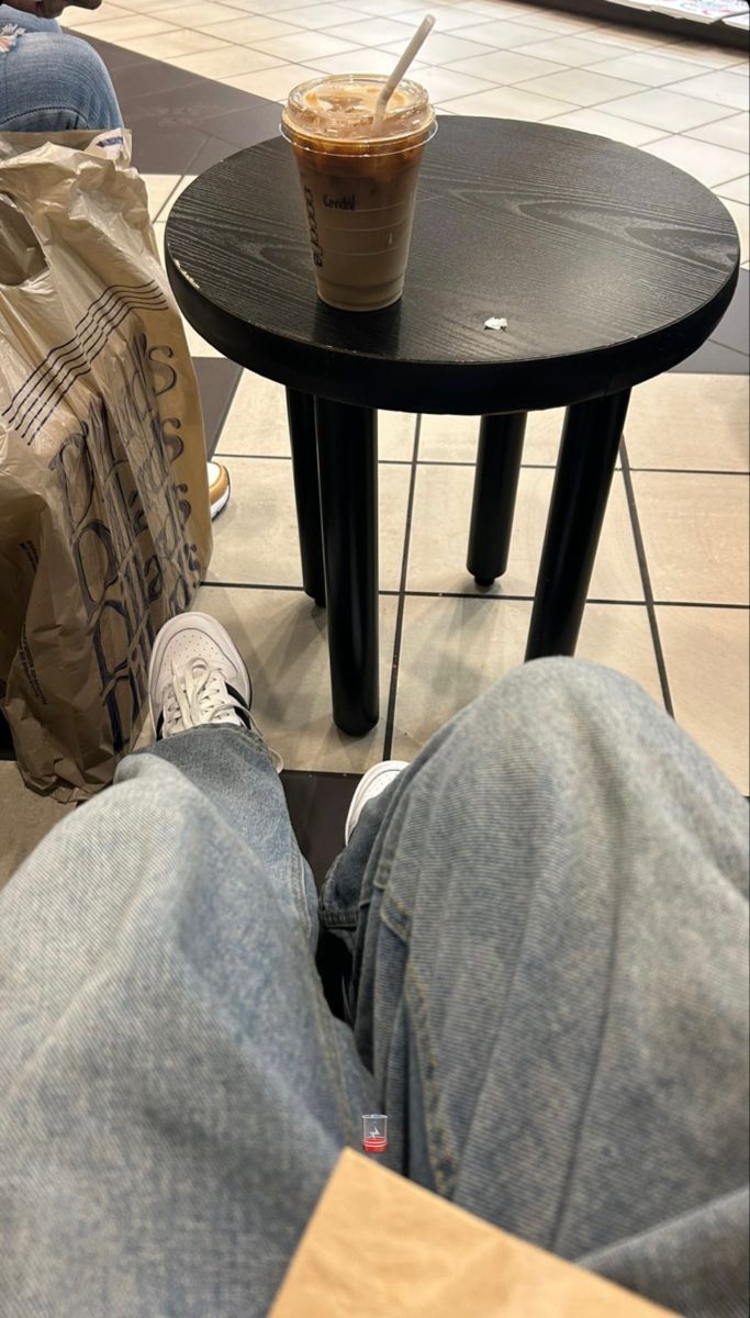 a person sitting on the floor with their feet up next to a table and bag