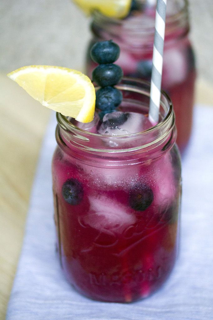 two mason jars filled with blueberries and lemonade on top of a table cloth