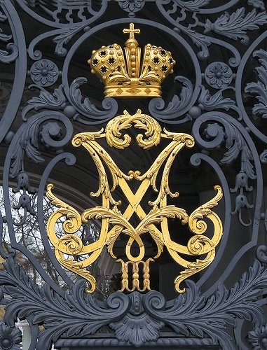 an ornate gold and black gate with a crown on top