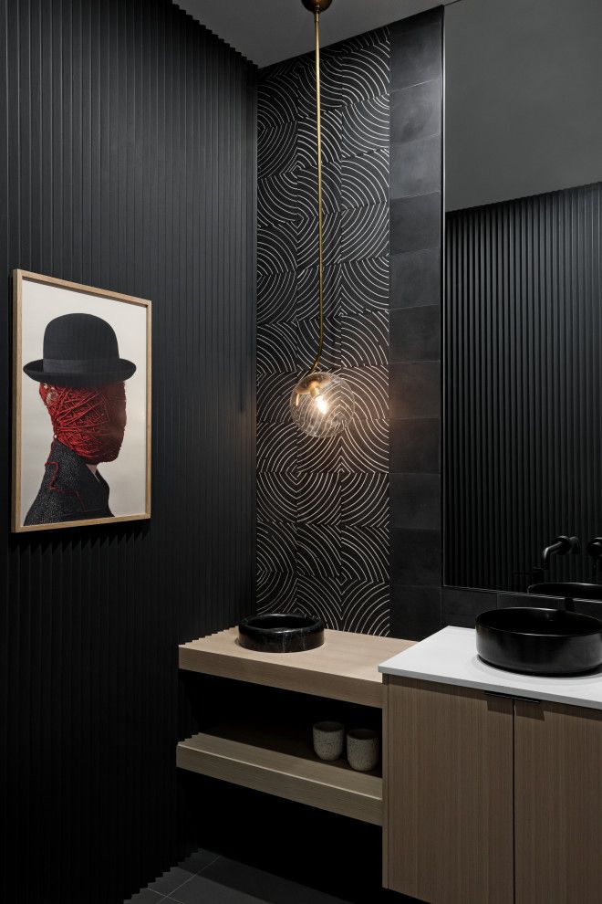 a bathroom with black walls and a painting hanging on the wall next to a sink