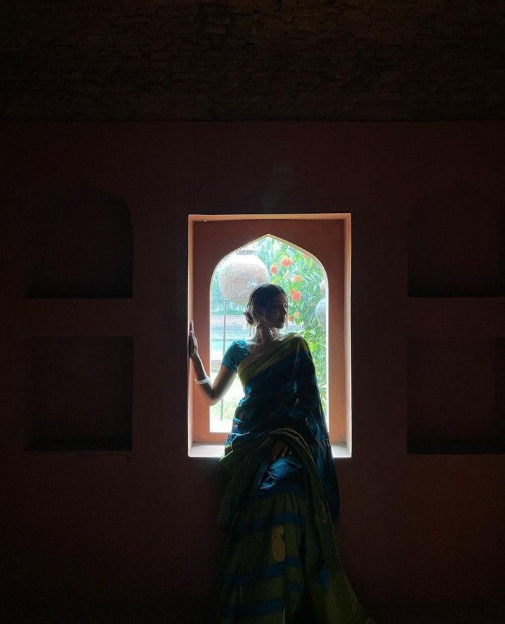 a woman standing in front of a window holding an umbrella