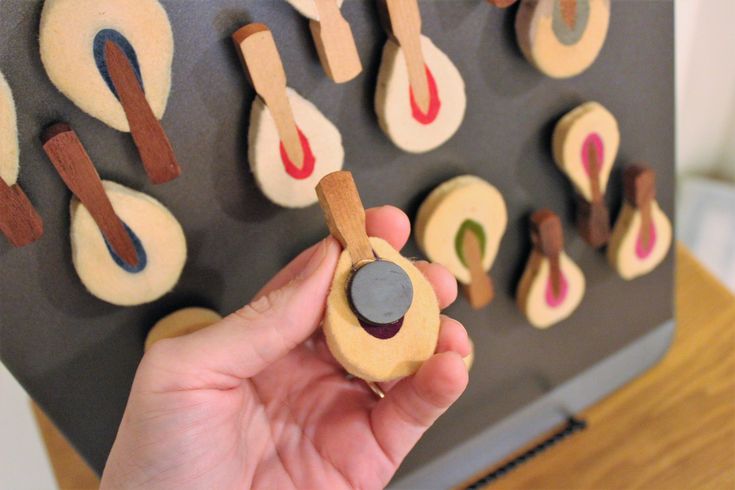 a person is holding some kind of magnets on a board with different shapes and sizes