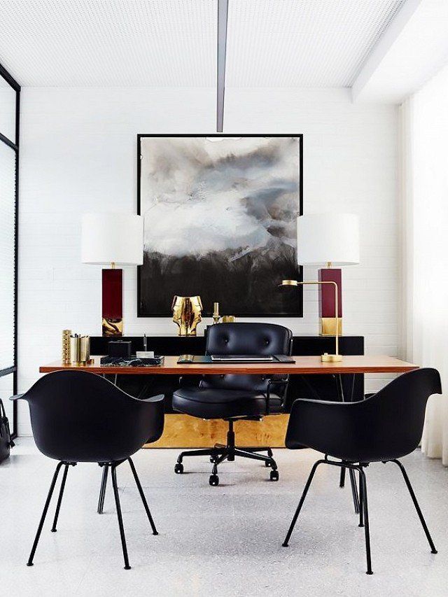 an office with black chairs and a large painting hanging on the wall above it's desk