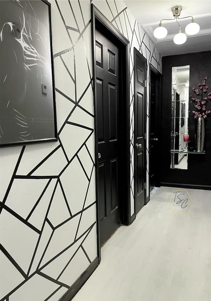 the hallway is decorated with black and white wallpaper, an art work on the door