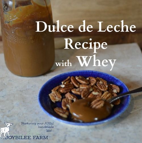 a blue bowl filled with pecans next to a jar of brown liquid on top of a table