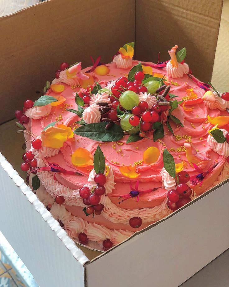 a cake in a box with flowers and leaves on the top is ready to be eaten