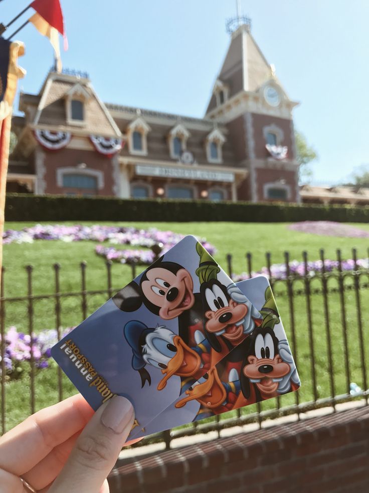 someone holding up a mickey mouse sticker in front of a building