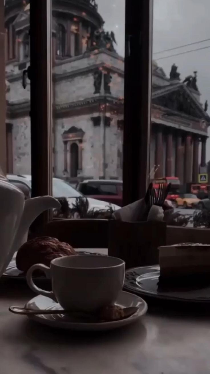 a cup of coffee sitting on top of a table next to a plate filled with cake