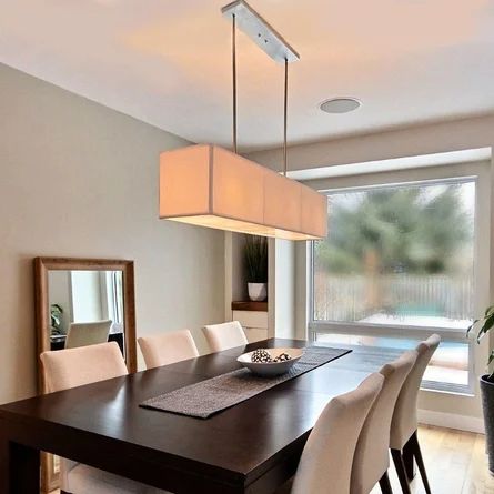 a dining room table with white chairs and a large rectangular light fixture hanging from the ceiling