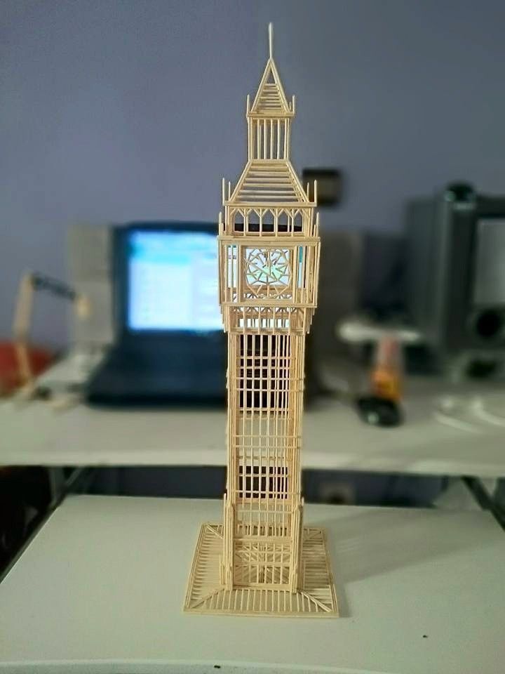 a wooden clock tower sitting on top of a desk