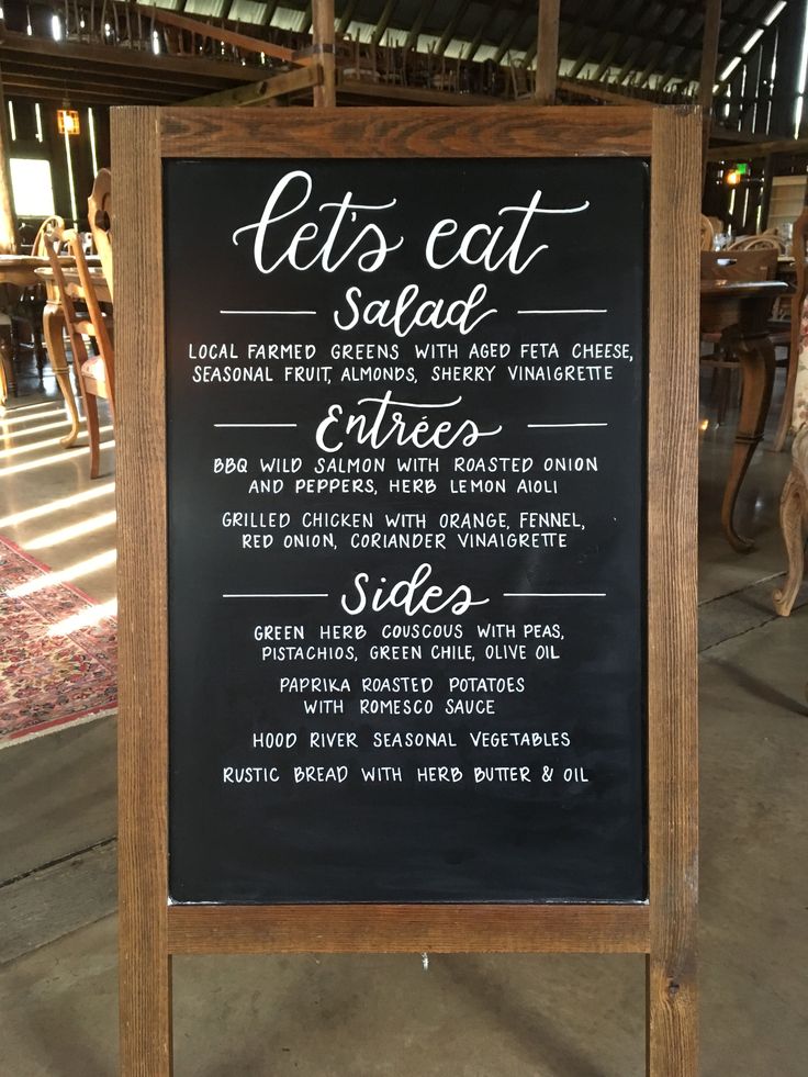 a blackboard sign with some writing on it in front of a table and chairs