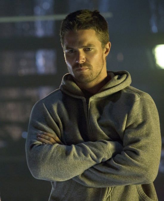 a man standing with his arms crossed in front of the camera, wearing a hoodie