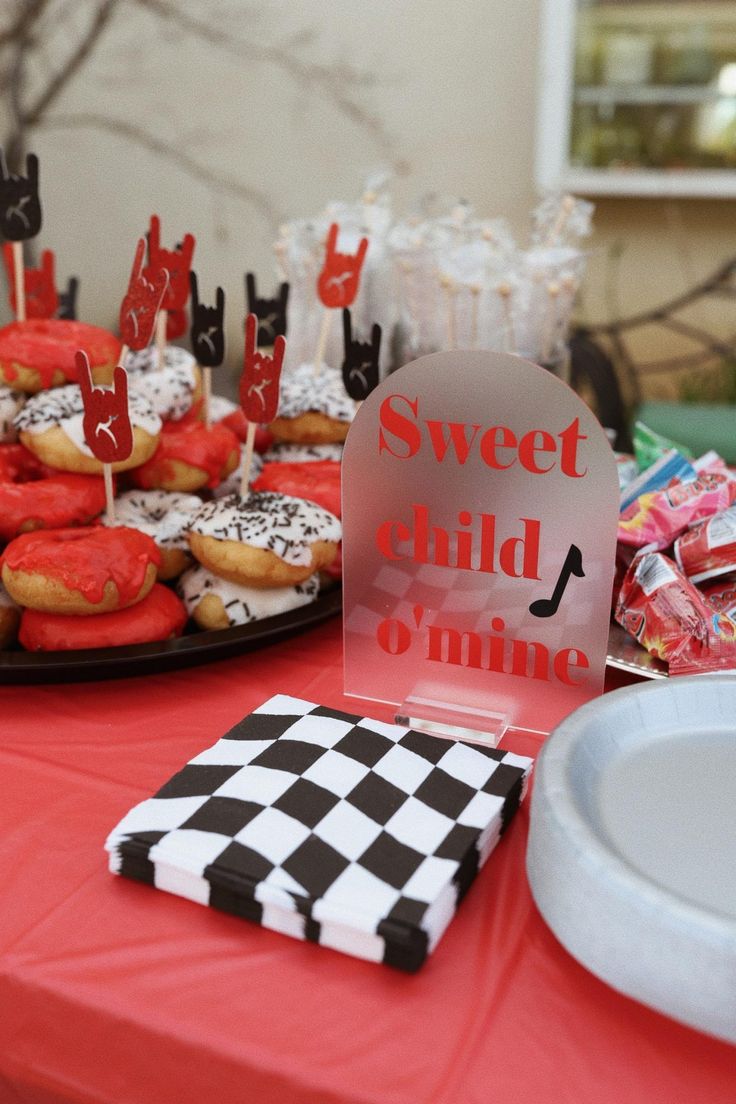 a table topped with lots of donuts covered in frosting and red icing