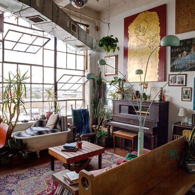 a living room filled with lots of furniture and plants on the wall next to a piano