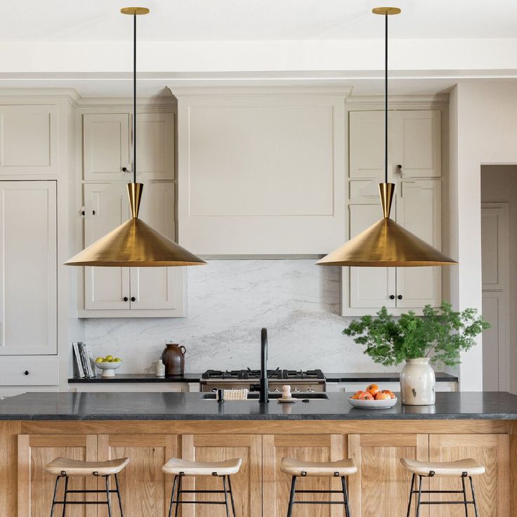 a kitchen with three pendant lights hanging over the island