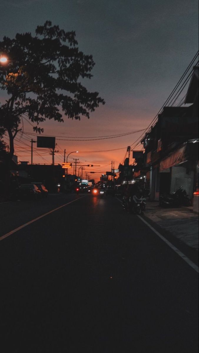 the sun is setting on an empty street