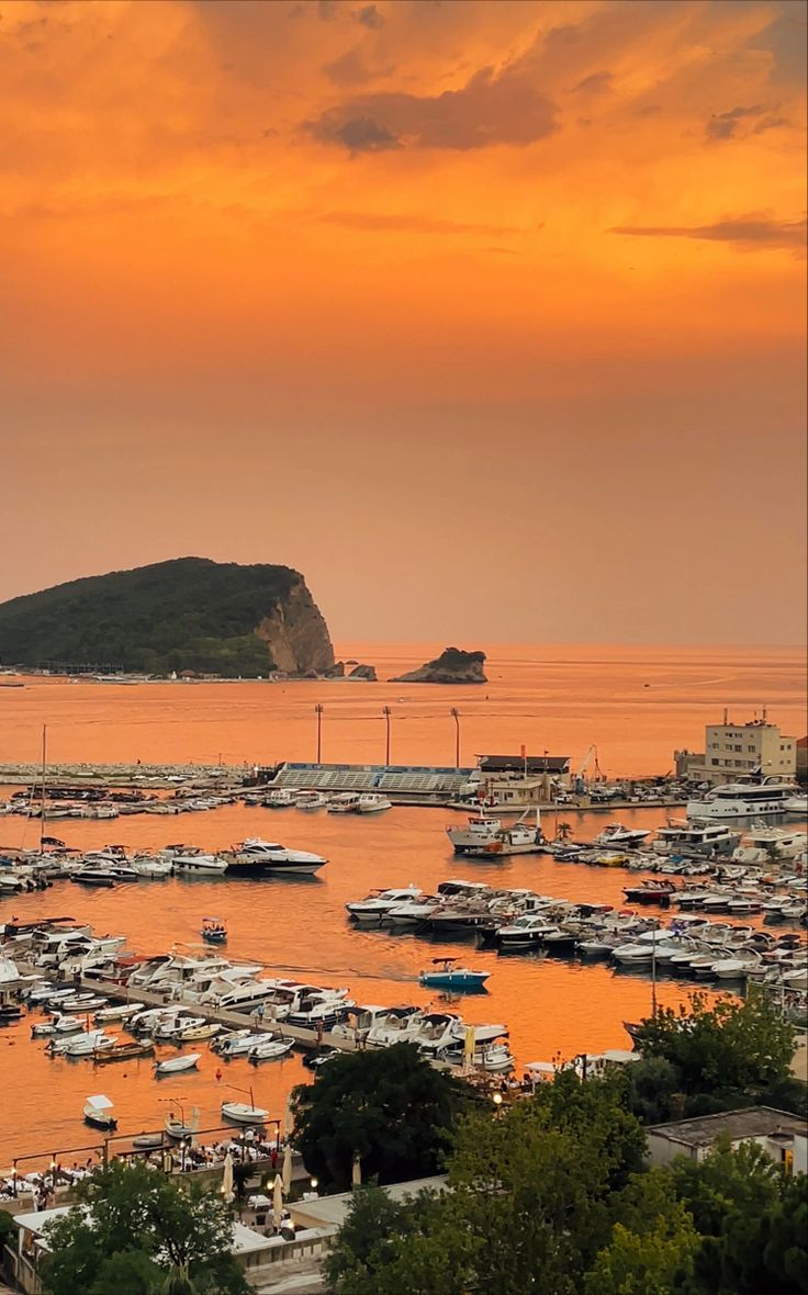 a harbor filled with lots of boats under a cloudy sky at sunset or sunrise time