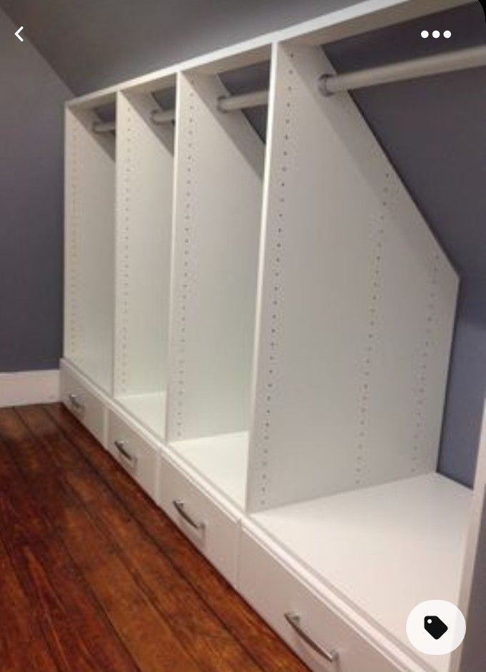 an empty room with some white shelves and drawers on the floor in front of a gray wall