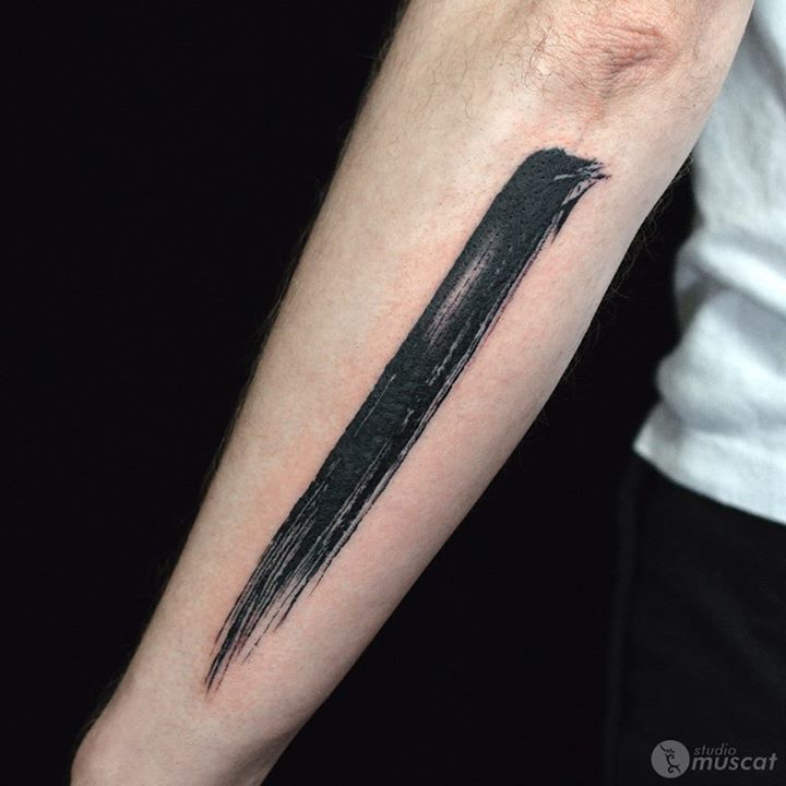 a person with a tattoo on their arm has a black pencil in the shape of an arrow