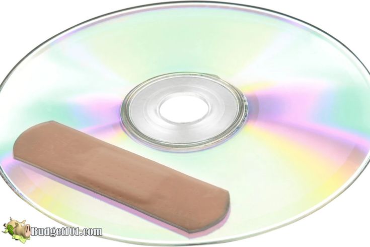 a cd with a wooden stick on top of it and a dvd disc in the background