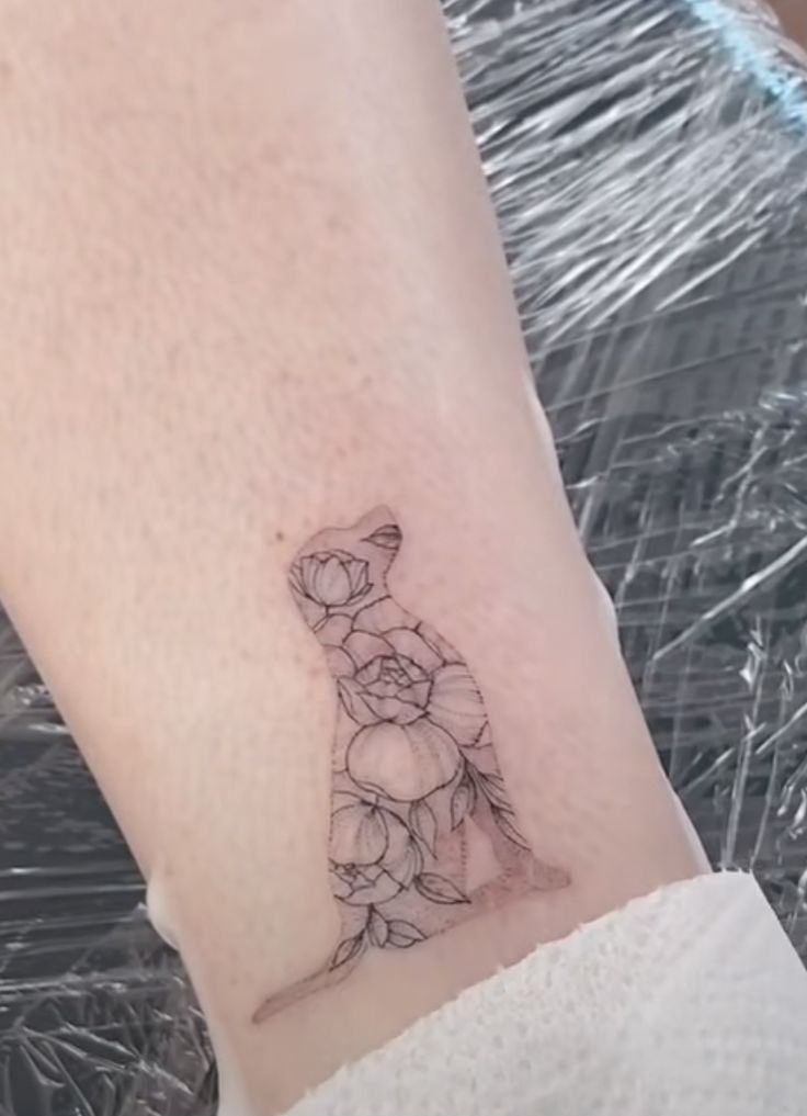 a small tattoo on the wrist of a woman's arm with flowers in it