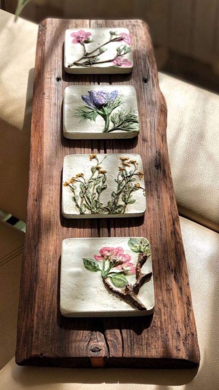 four coasters with flowers painted on them sitting on a wooden table next to a couch