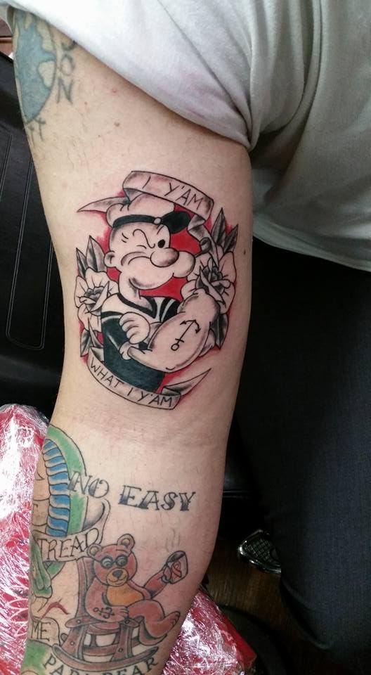 a man's arm with tattoos on it and an image of a cartoon character