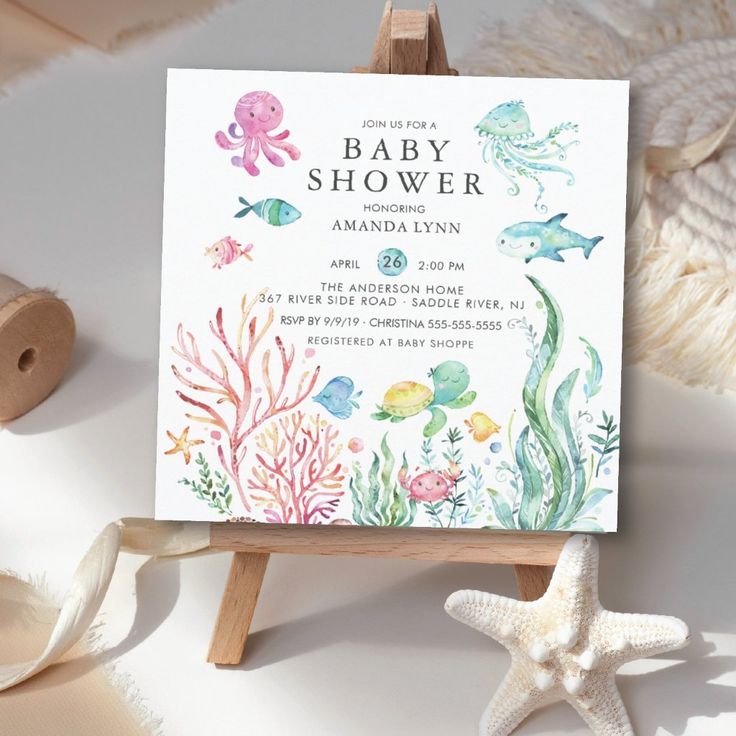 an ocean themed baby shower is displayed on a easel next to starfish and seashells