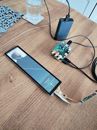 an electronic device sitting on top of a wooden table next to a charger and wires