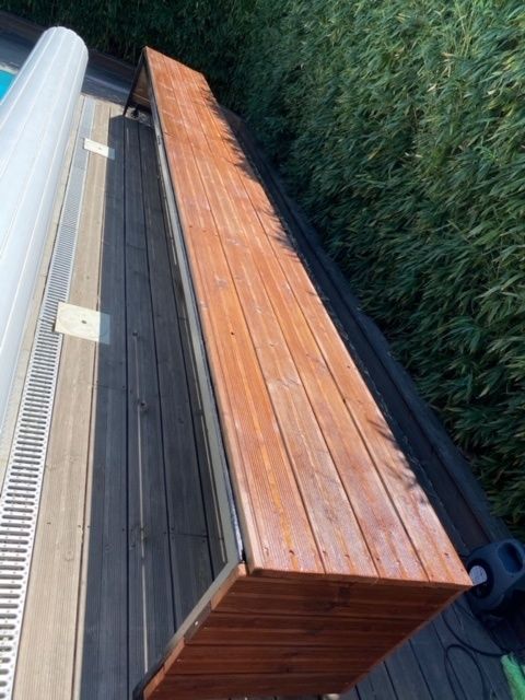 a wooden bench sitting next to a swimming pool on top of a hard wood floor