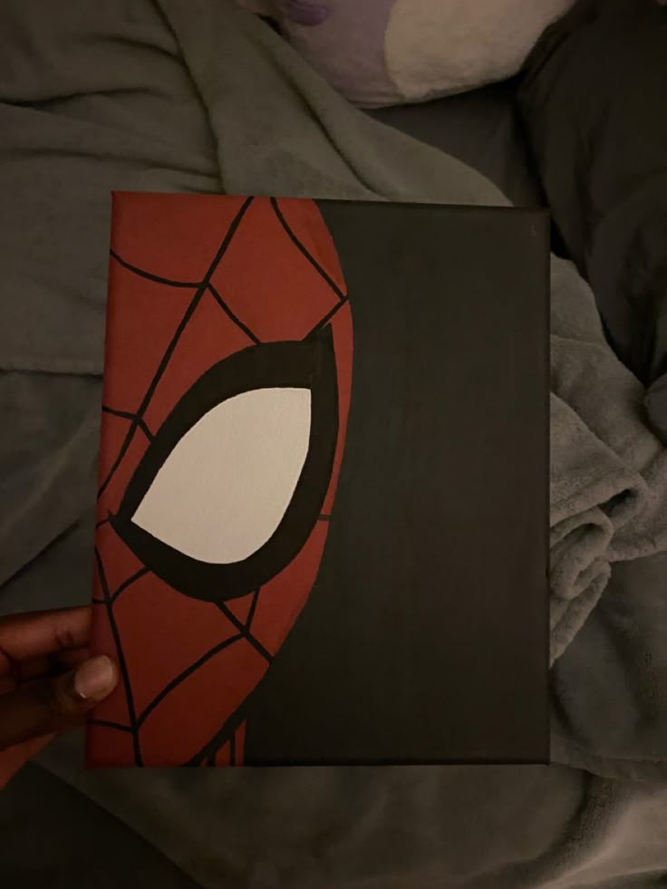 someone is holding up a book with a spiderman face on it